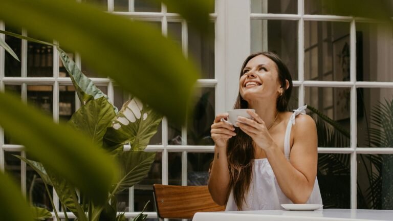 a woman sitting at a table drinking a cup of coffee
