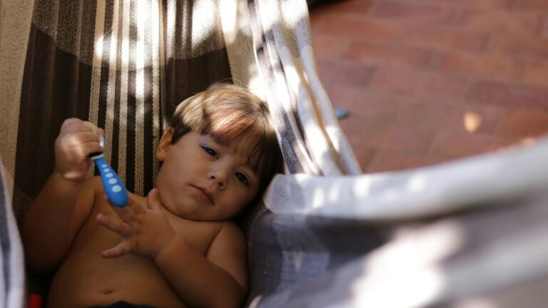 boy holding spoon lying in hammock