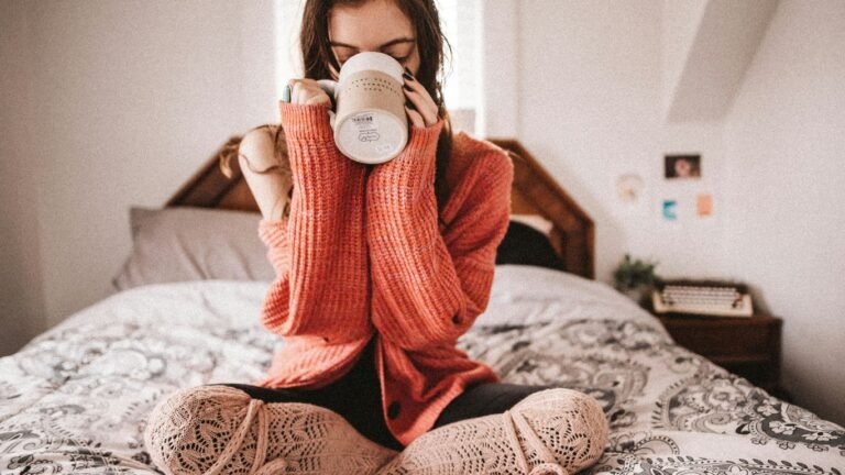 woman in red knit sweater holding white ceramic mug